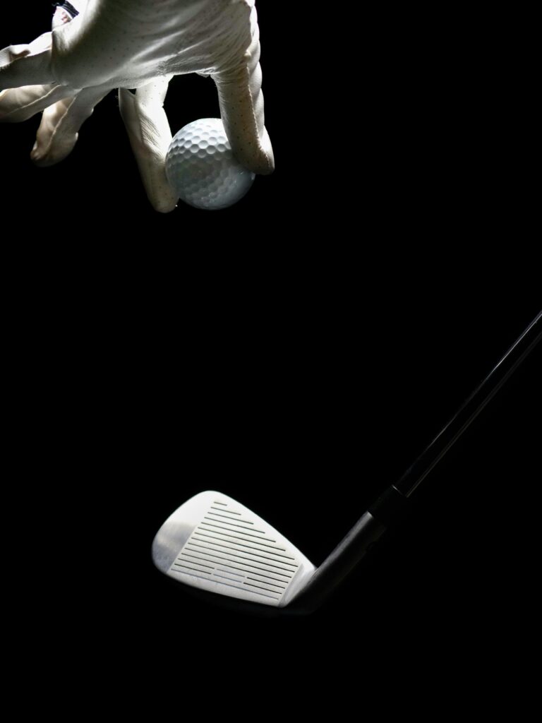 A hand dropping a golf ball on a golf iron. image