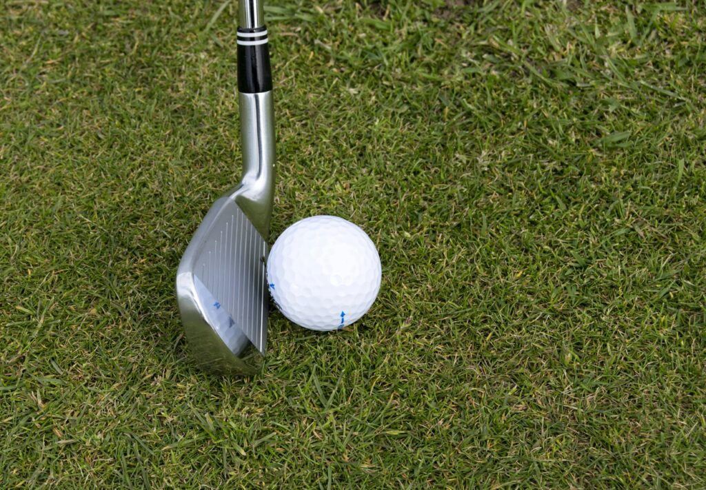 Golf Iron aligned to hit a golf ball on the grass image